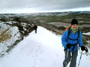 Camino de Santiago en invierno con peregrino caminando bajo frío, lluvia y silencio en Galicia