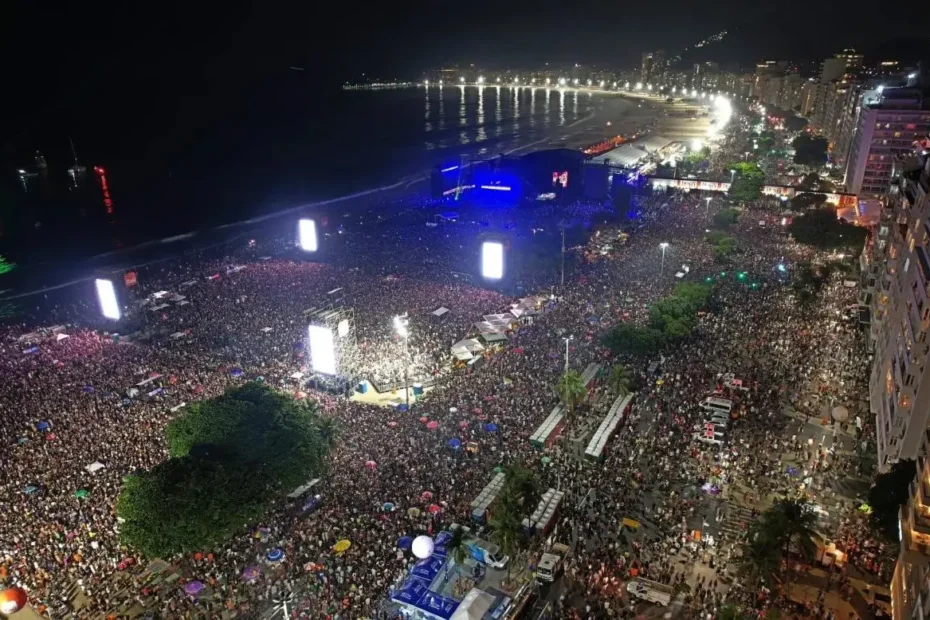 Multidão reunida na praia de Copacabana durante show noturno, com luzes e emoção coletiva representando a força da cultura latina.